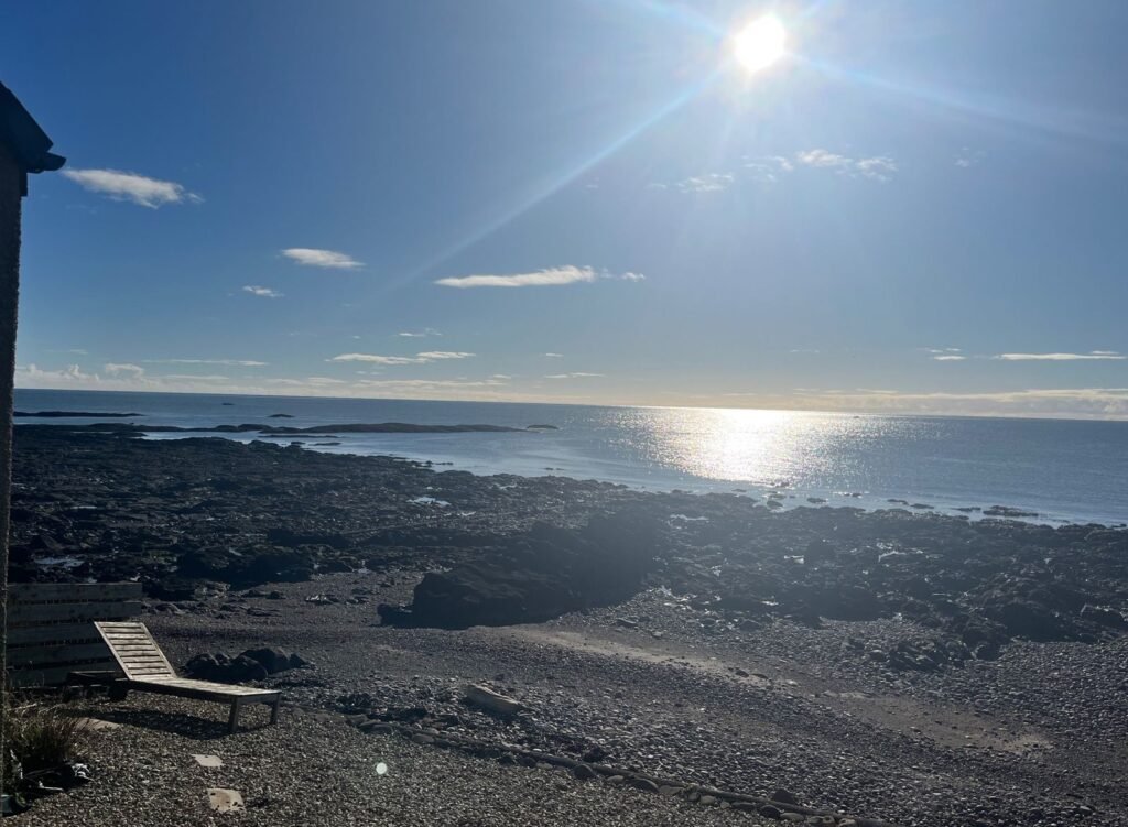 Sun and rays over the sea from the Johnshaven retreat, with a path of light on the water, paving stones and a lounger in the foreground
